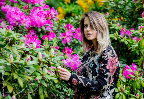 style woman near rhododendron flowers in a grarden in spring time