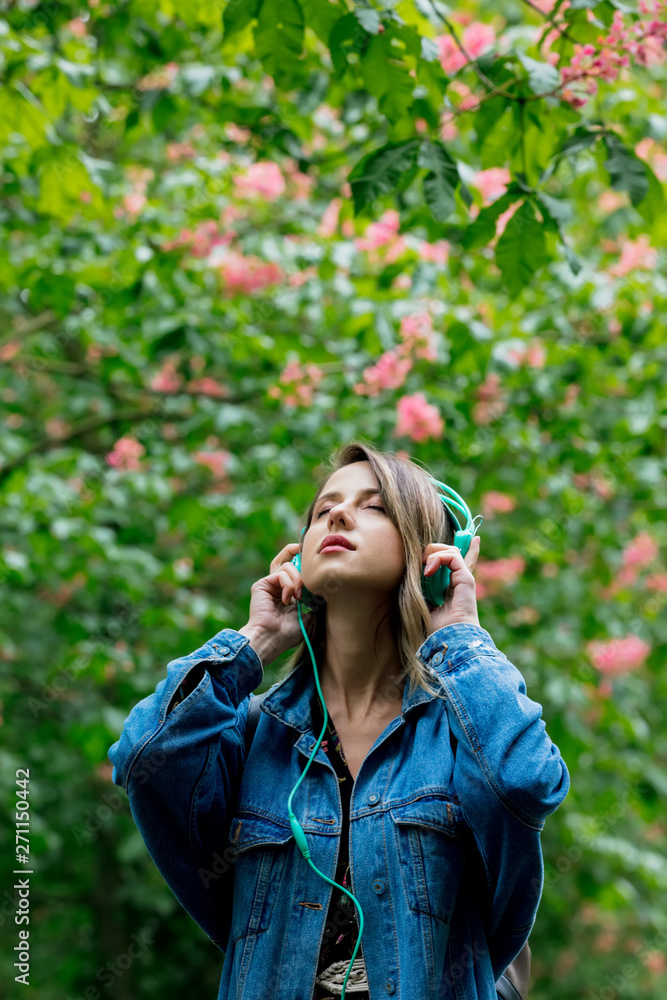 woman with a headphones at blossom trees on background in springtime woman with a headphones at blossom trees on background in springtime