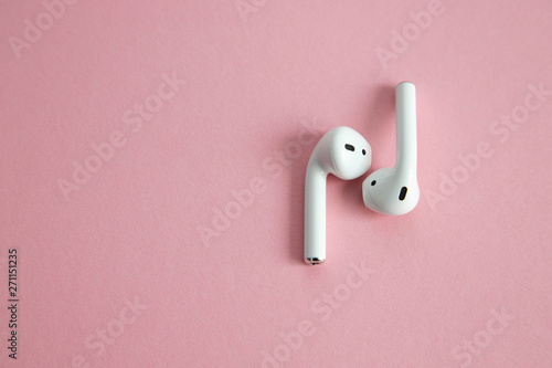 wireless white headphones without cord, lying next to each other on a pink background. Place for text photo