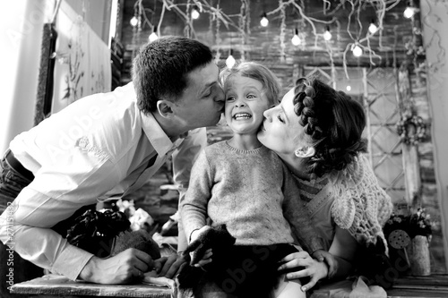 mom and dad kissing his little daughter.