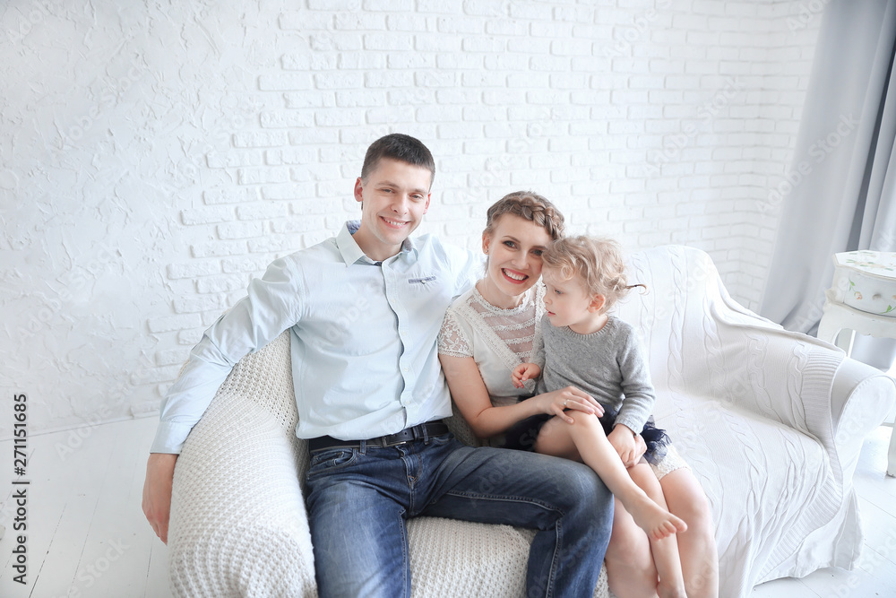 happy family with little daughter sitting on sofa