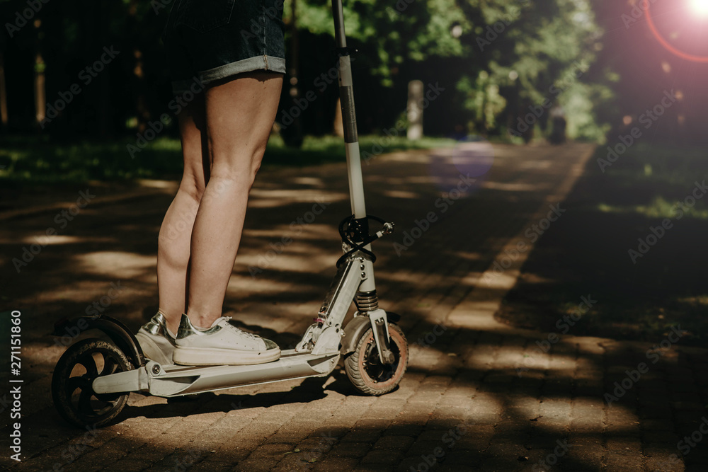 Obraz premium girl in white sneakers on the electric scooter in the city.
