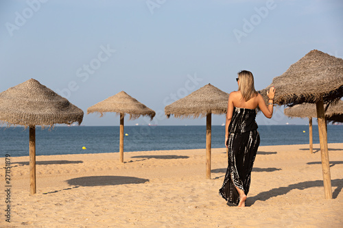 Mujer joven y rubia, con vestido largo en la playa. photo