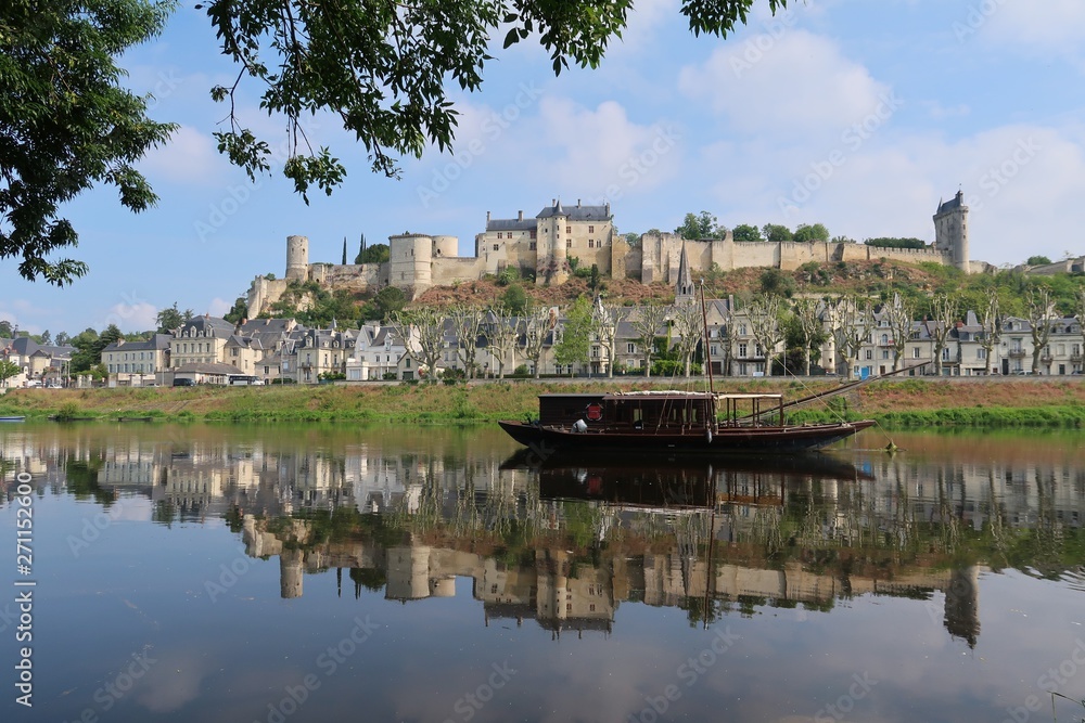 Obraz premium Chinon, panorama sur la ville et son château, avec son reflet sur la Vienne et un bateau traditionnel (France)