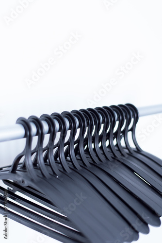 black plastic hangers hang on a light background. many different hangers.