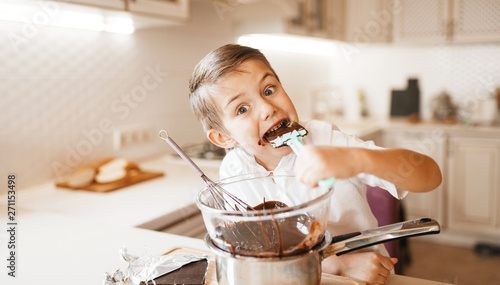 Young boy tastes melted chocolate in a bowl