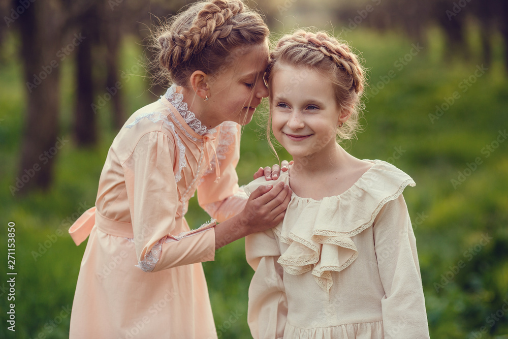 Beautiful cute girls in the garden, enjoying the arrival of spring, dresses in vintage style Beautiful cute girls in the garden, enjoying the arrival of spring, dresses in vintage style
