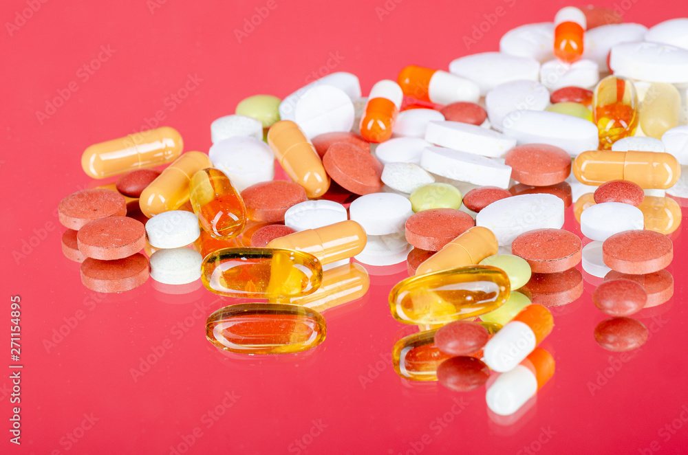 various pills on a red mirror glass background various pills on a red mirror glass background