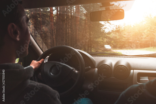 young guy driving a car during sunset outside the city