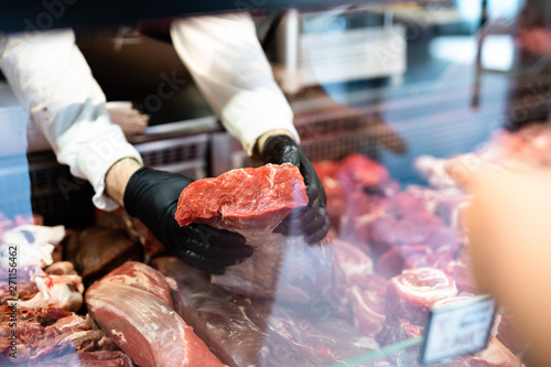 Closeup on butcher's hands in gloves working in butchery. photo