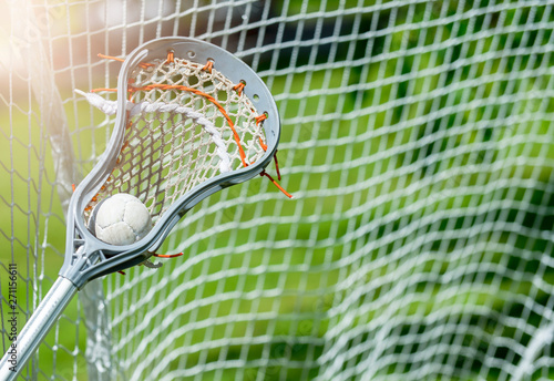 Abstract view of a lacrosse stick scooping up a ball. Sunny day photo