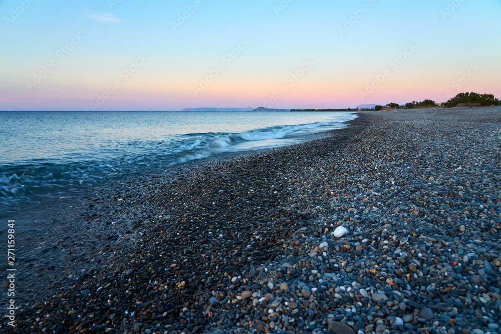 The sunset on the pebble beach with hills on the background, Kolymbari, Crete, Greece. The sunset on the pebble beach with hills on the background, Kolymbari, Crete, Greece.