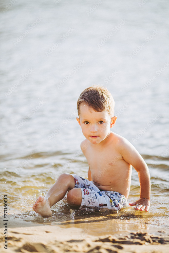 Theme is summer time and rest near the water. Little joyful Caucasian funny boy plays and enjoys in the river. The child is resting and swimming in the lake pond sandy beach Theme is summer time and rest near the water. Little joyful Caucasian funny boy plays and enjoys in the river. The child is resting and swimming in the lake pond sandy beach