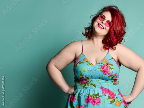 Plus-size fat woman with sincere smile stands with hands on her hips and looks at us on mint with free text copy space
