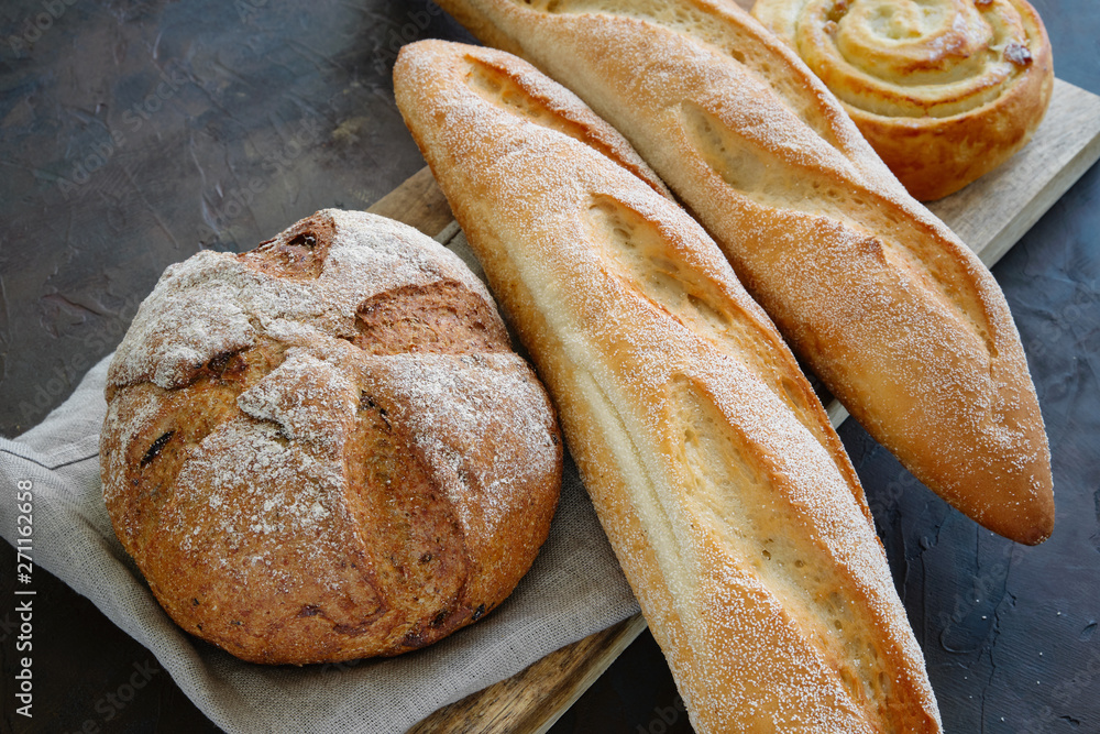 Freshly baked baguettes, bread and bun on a linen napkin.