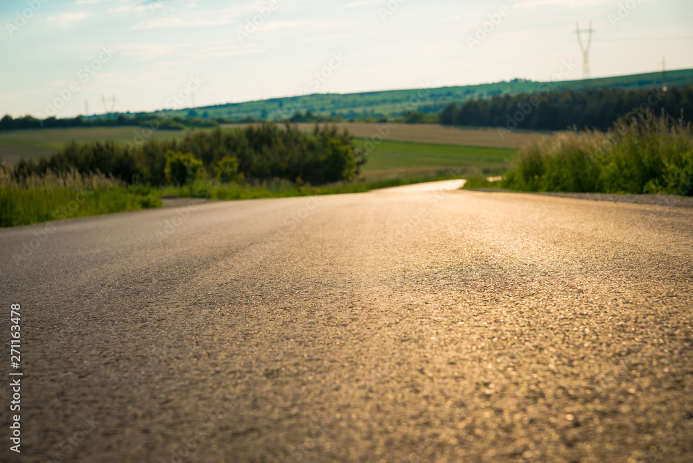 Close up of asphalt on country road. Asphalt texture on empty rural road down the hill Close up of asphalt on country road. Asphalt texture on empty rural road down the hill