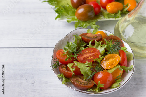 Fresh tomato and green salad in a plate on a wooden table ..