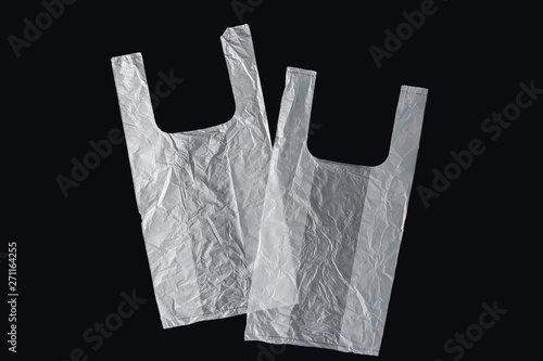 Plastic bag with handles, gloves, on a black background . Used plastic bag for recycling. Concept - ecology, planet pollution with plastic cellophane polyethylene