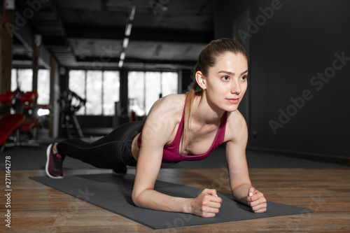 Close up of young pretty european muscular woman doing plank exercise indoor at the gym. Concept of health and sport lifestyle. Athletic Body..