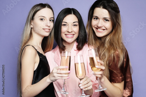 three beautiful girls dressed in pajamas drink champagne and have fun