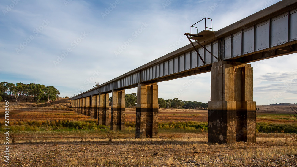 Diminishing perspective view of disused Railway Bridge over Joyces Creek its entry to Lake Cairn Curran on the Moolort Plains near Newstead, Victoria, Australia