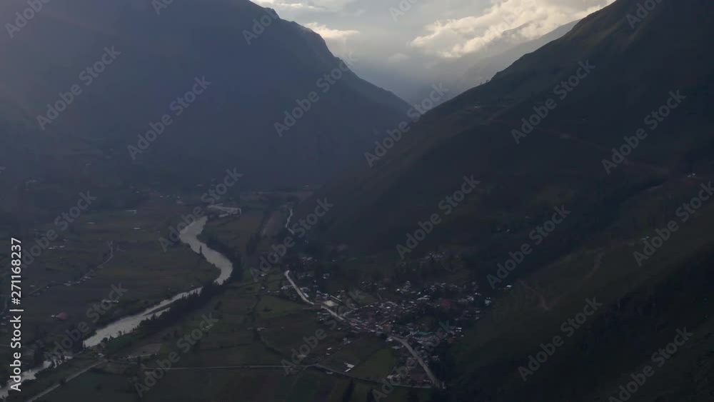Aerial shot of a small village in a valley, tilt up to reveal magnificent cloudscape around mountains Aerial shot of a small village in a valley, tilt up to reveal magnificent cloudscape around mountains