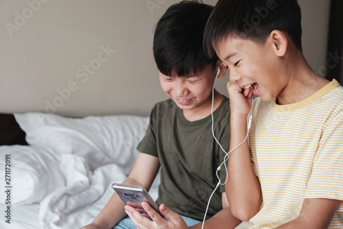  Tween boys using tablet and sharing earphones, listening to podcast, audio books, music, playing games, using internet technology for online learning, social distancing at home concept photo