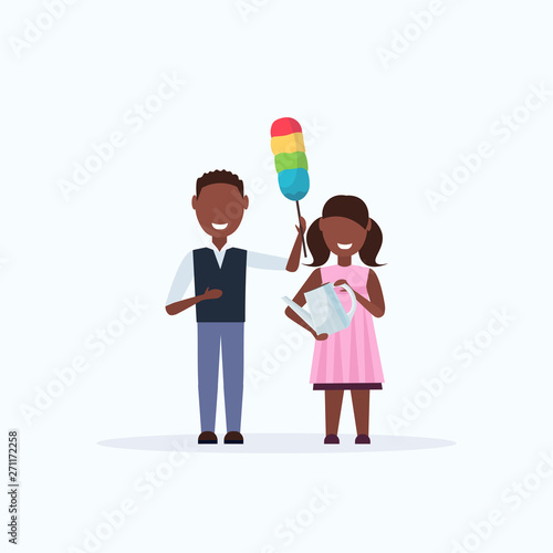 smiling children holding dust brush and watering can african american boy girl dusting cleaning housework concept full length flat white background