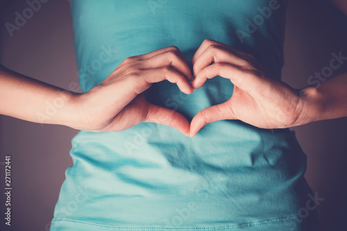 Woman hands making a heart shape on her stomach, healthy bowel degestion, probiotics  for gut health, leaky gut, Sign Language photo