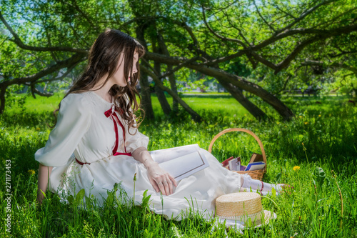 Woman in a white dress sitting under a tree lilacs.