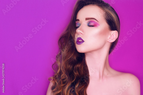 Fashion model woman creative pink and blue make up. Beauty art portrait of beautiful girl with colorful abstract makeup. Beautiful Eyes Glitter . Purple bright lips, long cerly hair. Pink background