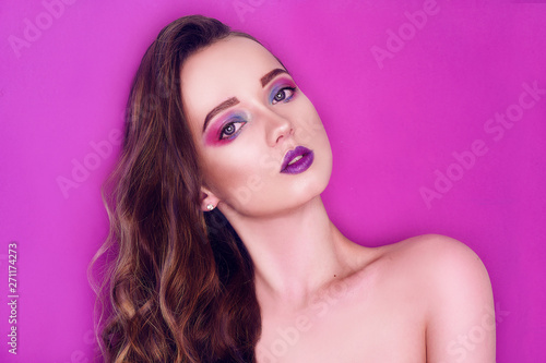 Fashion model woman creative pink and blue make up.  Beauty art portrait of beautiful girl with colorful abstract makeup. Beautiful Eyes Glitter . Purple bright lips, long cerly hair. Pink background