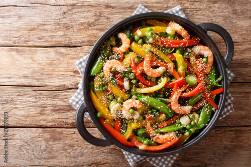 Fototapet Vegetable stir fry with shrimps and sesame close-up in a frying pan