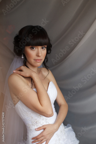 Beauty portrait of bride wearing fashion wedding dress with feathers with luxury delight make-up and hairstyle, studio indoor photo. 