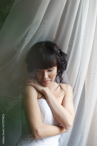 Beauty portrait of bride wearing fashion wedding dress with feathers with luxury delight make-up and hairstyle, studio indoor photo. 