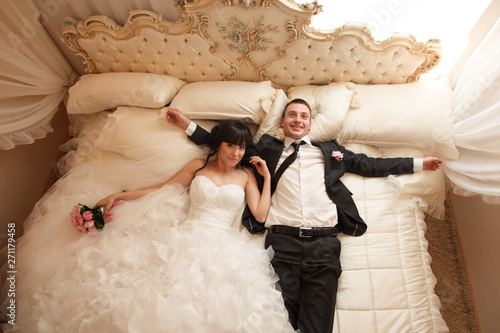 bride and groom having fun jumping on the bed joyful pillow fighting happiness