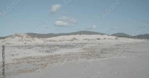 Beach with mountains in the background, few clouds in the sky photo