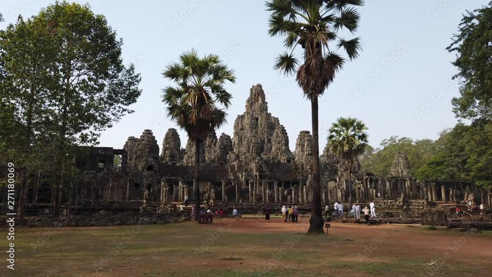 view of the Bayon Temple in Angkor, in the foreground walking tourists. view of the Bayon Temple in Angkor, in the foreground walking tourists.