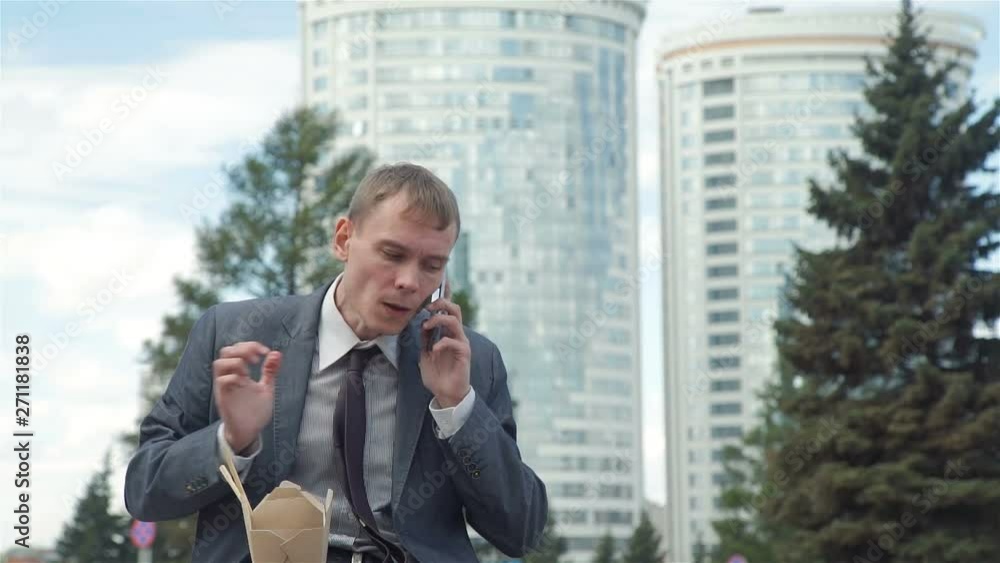 Businessman Having Lunch and Talking on Phone Outdoors. He is Continuing to Work during his Lunch Break. Lifestyle and Business Concept Businessman Having Lunch and Talking on Phone Outdoors. He is Continuing to Work during his Lunch Break. Lifestyle and Business Concept