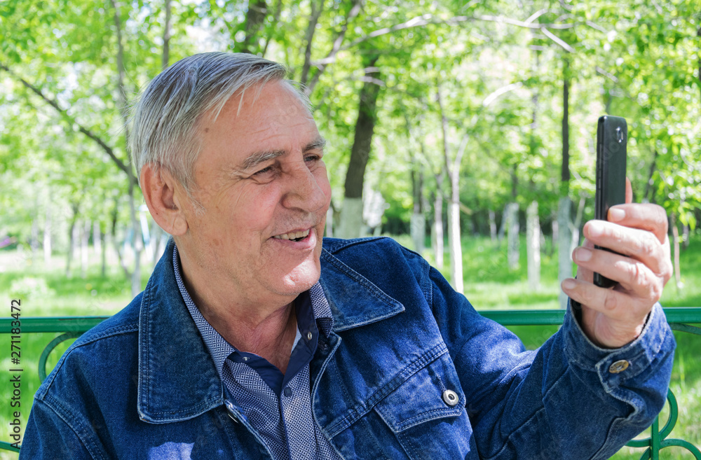 Elderly man with a phone in the park. Elderly man with a phone in the park.