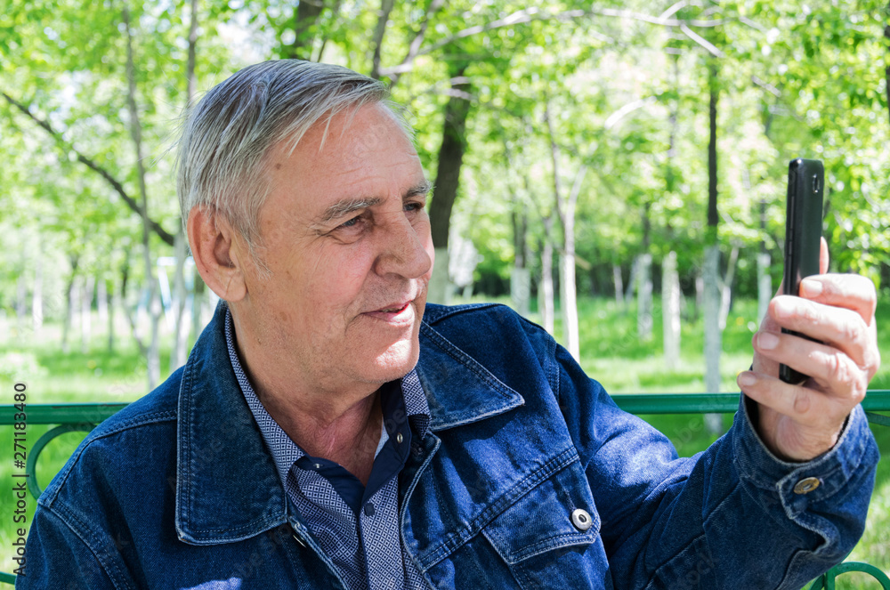 Elderly man with a phone in the park. Elderly man with a phone in the park.