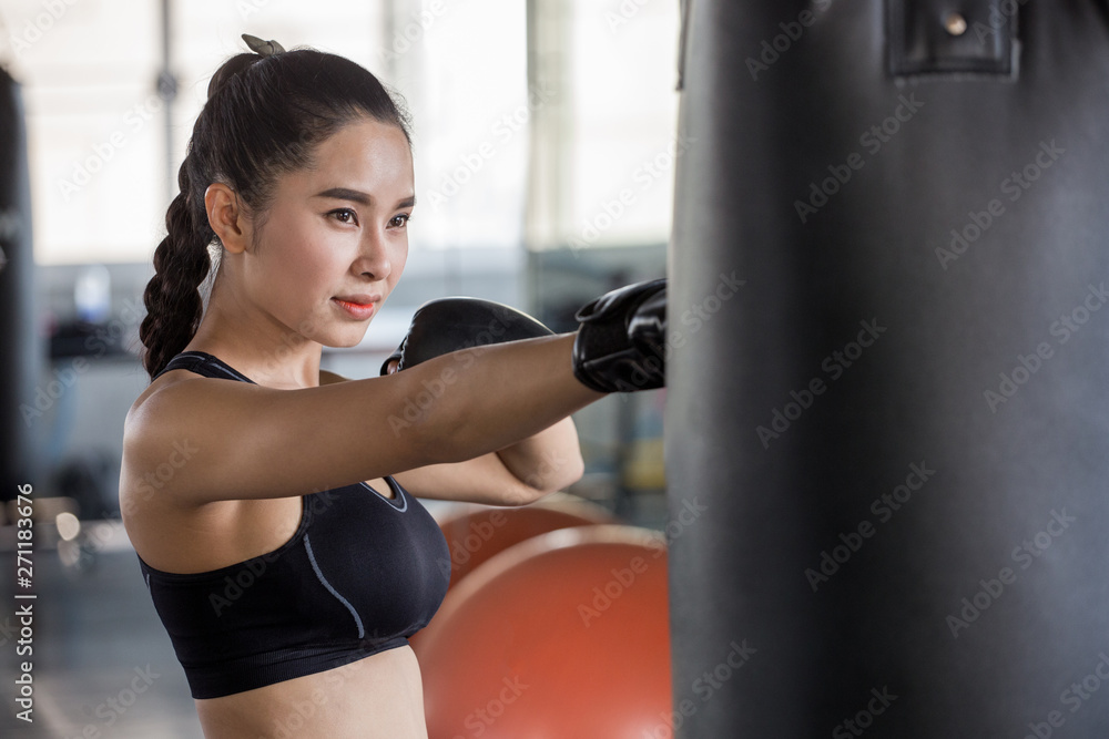 Beautiful athletic Asian Boxer woman punching bag with Boxing Gloves in fitness gym.sport girl in sportswear exercising or workout