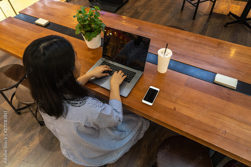 Woman freelancer typing laptop computer next to cellphone Woman freelancer typing laptop computer next to cellphone