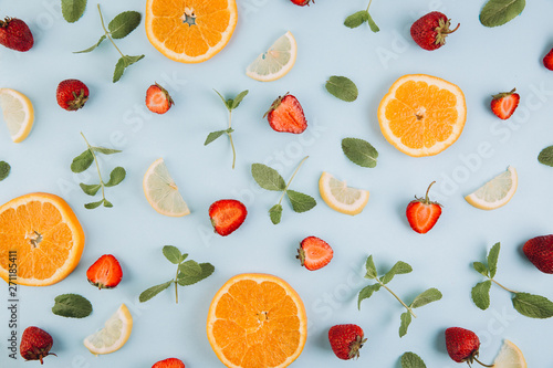 Summer colorful flat lay. Pattern made of citrus fruits  leaves and strawberries on the blue wooden table