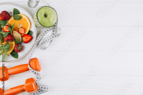 Diet plan, menu or program, tape measure, water, dumbbells and diet food of fresh fruits on white background, weight loss and detox concept, top view
