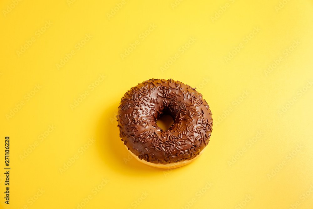 chocolate donut on yellow background top view