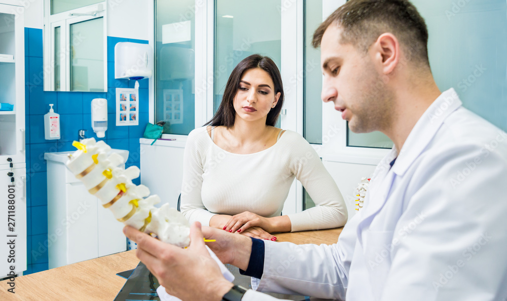 Fototapeta premium Orthopedist showing spine model to patient in hospital
