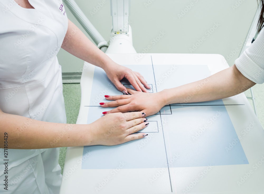 Radiologist and patient in a x-ray room. X-ray of human hand. Classic ceiling-mounted x-ray system. Radiologist and patient in a x-ray room. X-ray of human hand. Classic ceiling-mounted x-ray system.