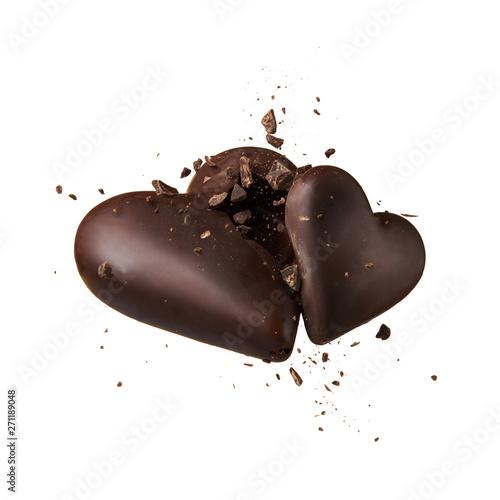 Two chocolate heart on a beige background. Hearts collide and break up into crumbs. High-speed shooting.