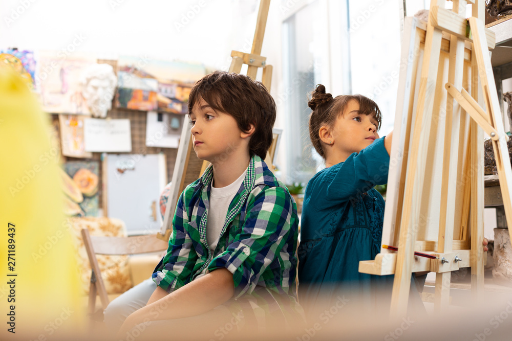 Obraz premium Dark-haired boy feeling bored during art lesson at school